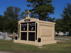 Four-space deluxe mausoleum with cross, granite inlays in the columns, vases on pedestals in Pascagoula, MS