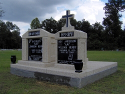 Single deluxe mausoleum with fluted columns and matching headstone with a cross and two vases on a foundation/slab