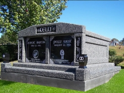 Side-by-side deluxe mausoleum deep gray with engraved inlays in the columns, vases on pedestals, step-up trim pieces on a foundation/slab in Taylorsville, MS