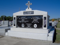 Side-by-side deluxe mausoleum with cross, engraved granite inlays in the columns, step-up trim pieces on a foundation/slab in Lafayette, LA