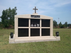 Six-space wide mausoleum with cross, fluted columns, vases on pedestals, step-up trim pieces on a foundation in Raiford, FL