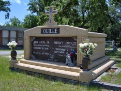 Side-by-side deluxe mausoleum with a cross, fluted columns, vases on pedestals, step-up trim pieces on a foundation/slab in Biloxi, MS