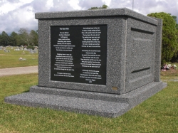 The back of a four-space deluxe mausoleum deep gray with large engraved panel and large step-up trim in Pascagoula, MS