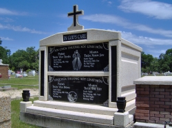 Four-space deluxe mausoleum with cross, with granite inlays in the columns, vases on pedestals, step-up trim pieces on a high foundation in Biloxi, MS