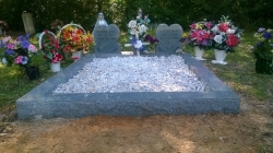 Two heart shape upright headstones with a vase and granite coping