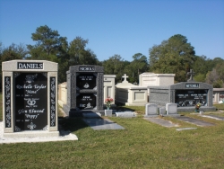 Deluxe over-and-under (stack) white mausoleum with engraved granite inlays in the columns, a deluxe over-and-under deep gray mausoleum with fluted columns, and a deluxe side-by-side deep gray mausoleum with fluted columns in Pascagoula, MS