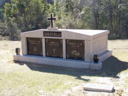 Three-space wide mausoleum with cross and fluted columns, vases on pedestals in Quincy, FL