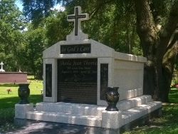 Single deluxe mausoleum engraved granite inlays in the columns and a cross and vases on pedestals with step-up trim pieces on a foundation/slab in Atlantic Beach, FL